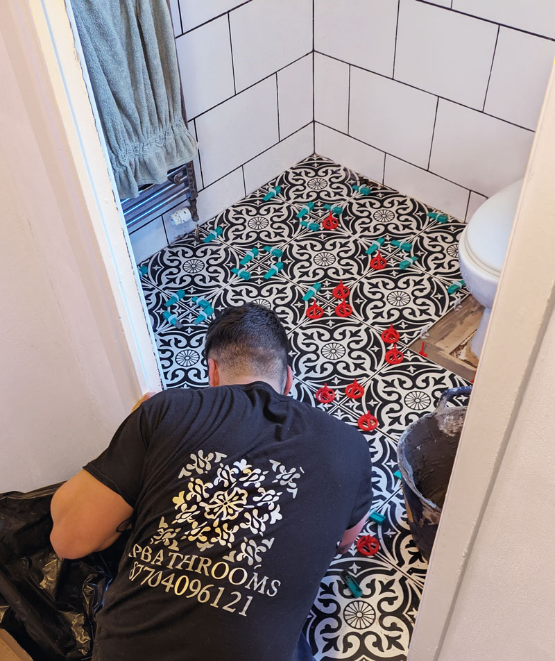 Alex Rowland tiling a bathroom floor